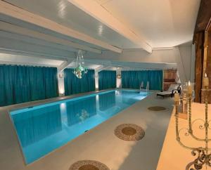 una gran piscina en una casa con cortinas azules en 7eme ciel - Tiny House avec Grande Piscine intérieure chauffée toute l'année, en Marais-Vernier