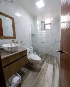 a white bathroom with a toilet and a sink at Hermosa Casa de Playa Machalilla in Machalilla