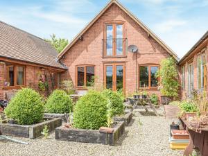 a brick house with a garden in front of it at The Milking Barn in Craven Arms