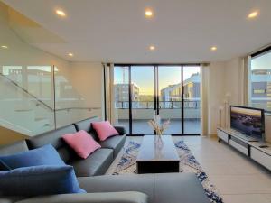 a living room with a couch and a tv at Spacious 3-Bed Penthouse with Perfect View in Sydney