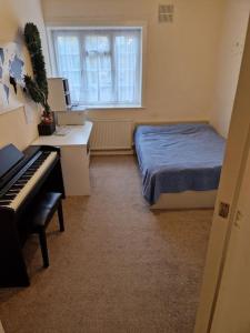 - une chambre avec un lit, un bureau et un piano dans l'établissement Double room for One Person in 3 beds flat, à Londres