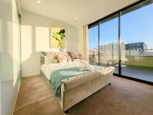 ein Schlafzimmer mit einem Bett und einem großen Fenster in der Unterkunft Spacious 3-Bed Penthouse with Perfect View in Sydney