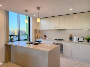 uma grande cozinha com armários brancos e uma grande janela em Spacious 3-Bed Penthouse with Perfect View em Sydney