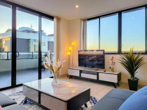 ein Wohnzimmer mit einem TV und einem Tisch in der Unterkunft Spacious 3-Bed Penthouse with Perfect View in Sydney