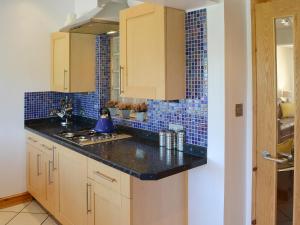 a kitchen with wooden cabinets and blue tiles on the wall at Beachcomber in Mundesley