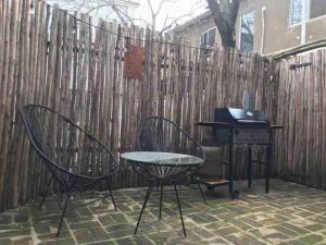 una parrilla y sillas frente a una valla en Casa particular con patio remodelada a nuevo en San Antonio de Areco