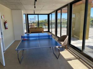 una mesa de ping pong azul en una habitación con ventanas en Edificio nuevo frente al mar, en Punta del Este