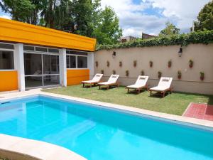 a swimming pool with chairs next to a building at La Casa del Parque B&B in Mendoza