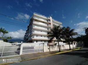 un grand bâtiment blanc avec un palmier devant dans l'établissement excelente Cobertura no centro de Bertioga, à Bertioga