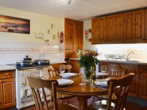 cocina con mesa de madera con sillas y comedor en West End Cottage en Carrbridge