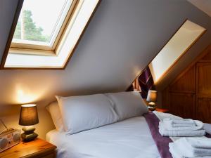 Schlafzimmer mit einem weißen Bett und einem Dachfenster in der Unterkunft West End Cottage in Carrbridge