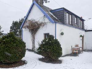 a white house with a blue roof in the snow at West End Cottage in Carrbridge