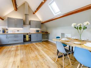 una cucina con tavolo in legno e sedie blu di Tadpole Cottage At Frog Hall a Tilston