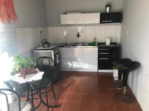 een keuken met een fornuis en een tafel met stoelen bij Quitinete com piscina em Balneário Pinhal in Pinhal