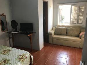 een woonkamer met een bank en een raam bij Quitinete com piscina em Balneário Pinhal in Pinhal +5 foto's