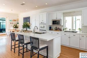 a kitchen with white cabinets and a kitchen island with chairs at Malibu Road Beachfront Charmer in Malibu