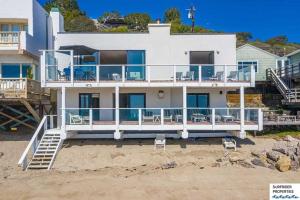 a large white house on the beach with chairs at Malibu Road Beachfront Charmer in Malibu