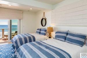 two beds in a bedroom with a view of the ocean at Malibu Road Beachfront Charmer in Malibu