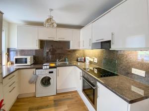 a kitchen with white cabinets and a washing machine at Largs Brisbane Cottage in Largs