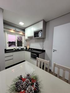 uma cozinha com uma mesa branca com flores em Apartamento Residencial Villa di Vienna em Nova Petrópolis