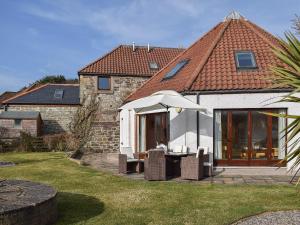 a house with a table and chairs and an umbrella at The Roundel in Leuchars