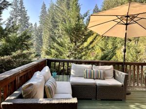a patio with two chairs and an umbrella on a deck at Raven Haven Lodge by NW Comfy Cabins in Leavenworth