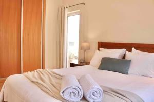 ein Schlafzimmer mit einem weißen Bett und Handtüchern darauf in der Unterkunft Ocean Terrace - Private Patio with BBQ & Sea view in Nazaré