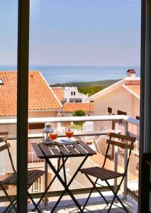 einen Balkon mit einem Tisch mit zwei Gläsern darauf in der Unterkunft Ocean Terrace - Private Patio with BBQ & Sea view in Nazaré