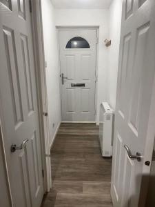 a hallway with a white door and a wooden floor at Modern studio apartment with parking in Chatham