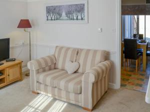 a living room with a couch and a television at Courtyard Cottage in Framlingham