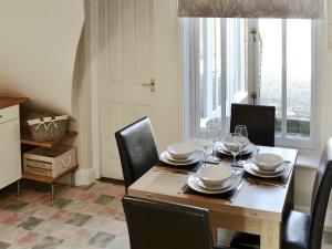 a dining room with a table and chairs and a window at Courtyard Cottage in Framlingham