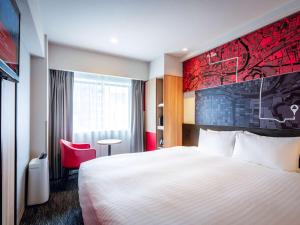 a hotel room with a bed and a red wall at ibis Osaka Umeda in Osaka