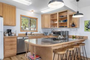 Una cocina con gabinetes de madera y una isla con taburetes de bar. en Rhodie House by NW Comfy Cabins, en Leavenworth