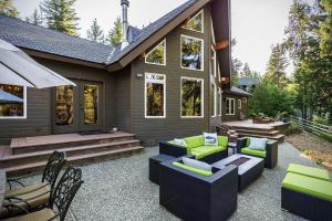 a patio with couches and chairs in front of a house at Riffle River Lodge by NW Comfy Cabins in Leavenworth