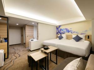 Habitación de hotel con 2 camas y sofá en Novotel Okinawa Naha en Naha