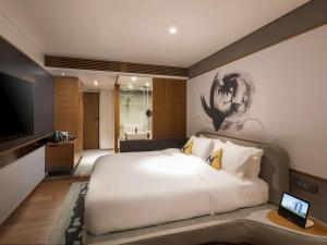 1 dormitorio con 1 cama blanca grande y TV en Novotel Ambassador Seoul Dongdaemun Hotels & Residences, en Seúl