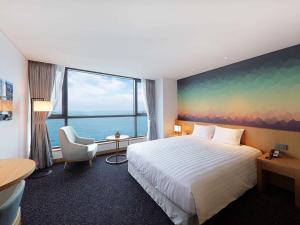 ウルサンにあるMercure Ambassador Ulsanのベッドと大きな窓が備わるホテルルームです。
