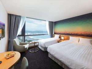 a hotel room with two beds and a large window at Mercure Ambassador Ulsan in Ulsan