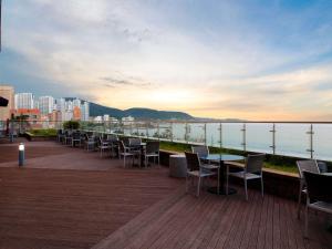 een rij tafels en stoelen op een terras met uitzicht op het water bij Mercure Ambassador Ulsan in Ulsan