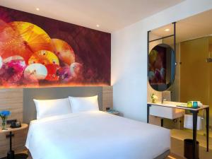 a bedroom with a large white bed and a bathroom at ibis Styles Bangkok Ratchada in Bangkok