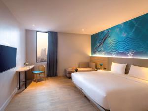 ein Hotelzimmer mit einem großen Bett und einem Schreibtisch in der Unterkunft ibis Styles Bangkok Ratchada in Bangkok