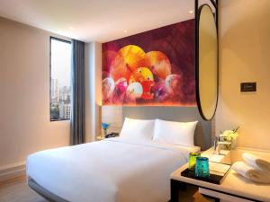 a hotel room with a white bed and a painting at ibis Styles Bangkok Ratchada in Bangkok