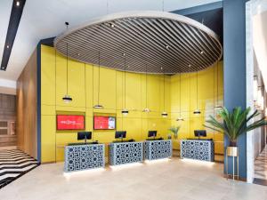 a lobby with a yellow wall in a building at ibis Bangkok Sukhumvit 24 in Bangkok