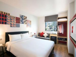 a bedroom with a large white bed and a bathroom at ibis Bangkok Sukhumvit 24 in Bangkok