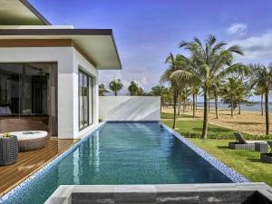 a swimming pool in front of a villa at Mövenpick Villas & Residences Phu Quoc in Phú Quốc