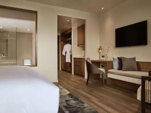 Habitación de hotel con cama, escritorio y TV. en Mövenpick Villas & Residences Phu Quoc en Phu Quoc