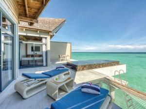 een huis met een terras met stoelen en de oceaan bij Mӧvenpick Resort Kuredhivaru Maldives in Manadhoo