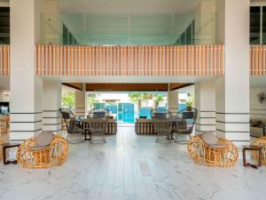 a lobby with chairs and tables and a patio at Mercure Langkawi Pantai Cenang in Pantai Cenang