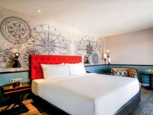 Schlafzimmer mit einem großen weißen Bett mit einem roten Kopfteil in der Unterkunft Mercure Langkawi Pantai Cenang in Pantai Cenang