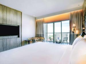ein Schlafzimmer mit einem großen weißen Bett und einem großen Fenster in der Unterkunft Mercure Langkawi Pantai Cenang in Pantai Cenang